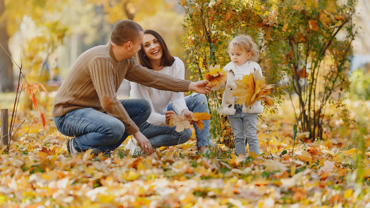Famille jouant dans les feuilles d'automne - illustration de l'article Communication non violente avec l'enfant