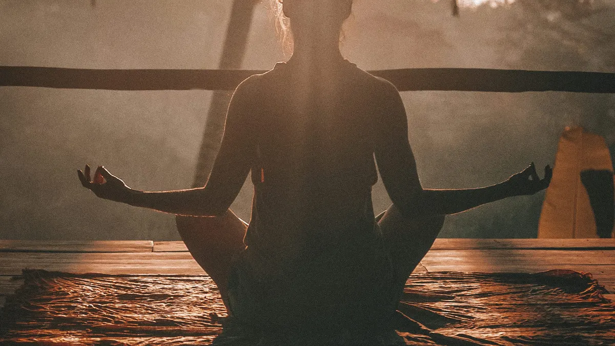 Personne en méditation face au soleil couchant - illustration de l'article Thérapeute ou coach : 7 clés pour bien gérer son stress