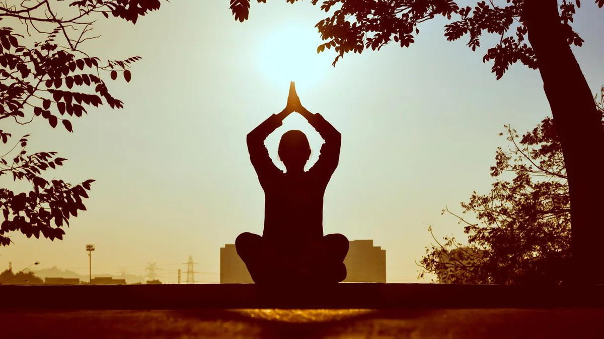 Silhouette en méditation au coucher du soleil - illustration de l'article Pratiques avancées de méditation