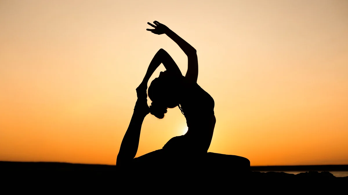 Silhouette en posture de yoga au coucher du soleil - illustration de l'article Bienfaits des retraites de méditation