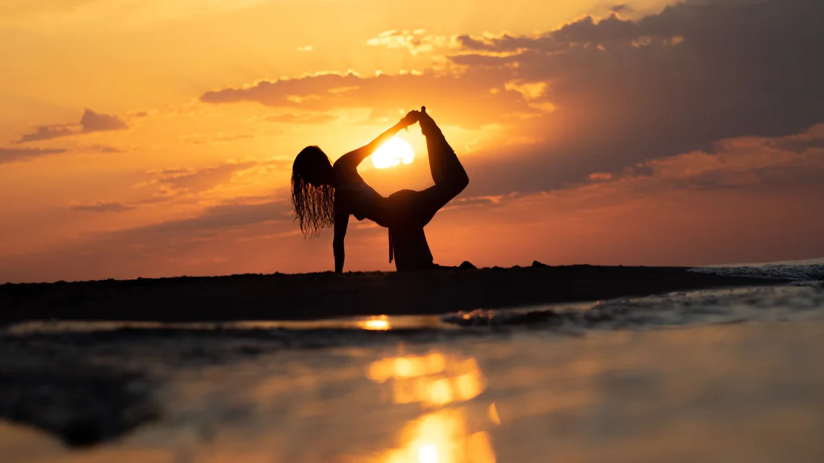 Posture de yoga au bord de l'eau au soleil couchant - illustration de l'article La croissance spirituelle en thérapie